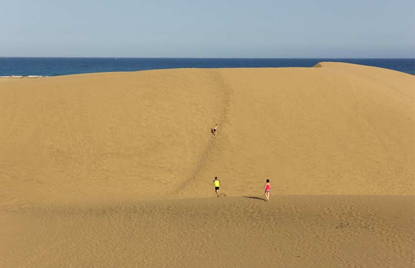 personas paseando por las dunas de maspalomas en gran canaria en verano